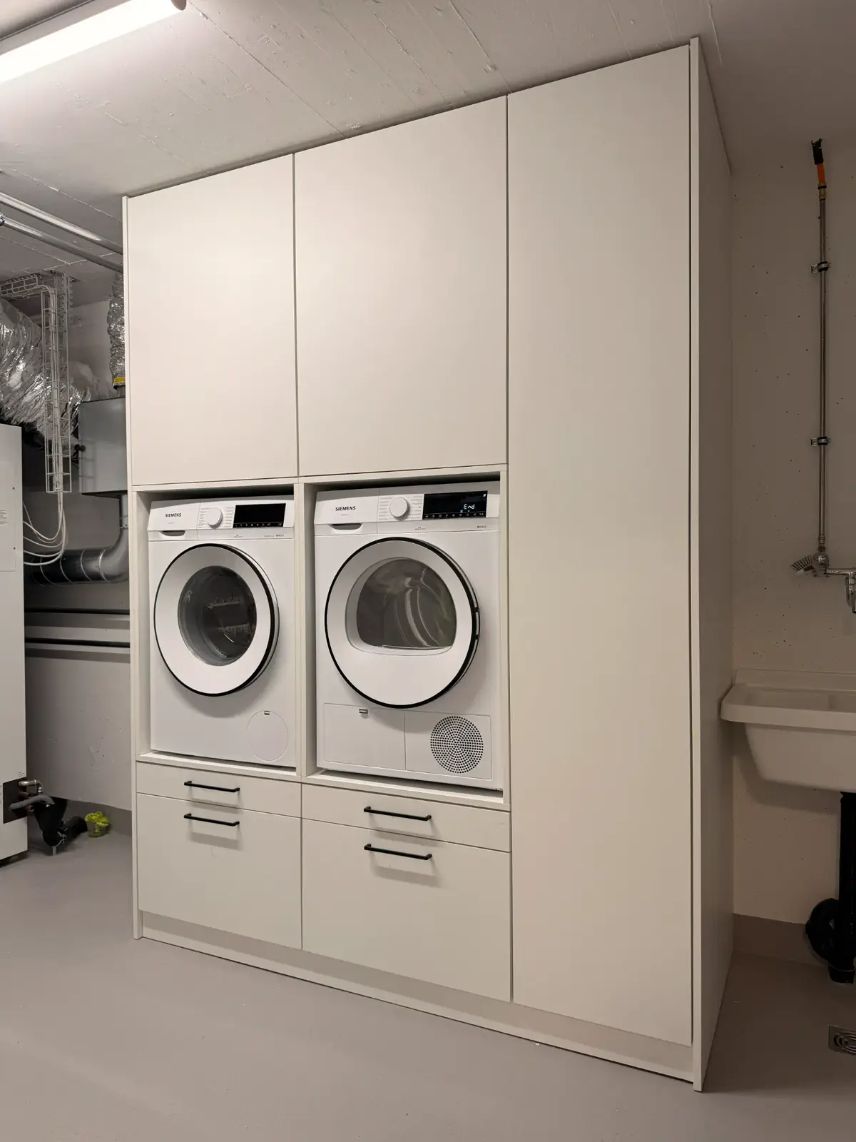 Einbauschrank für Waschmaschine und Trockner mit integriertem Stauraum und geschlossenen Fronten