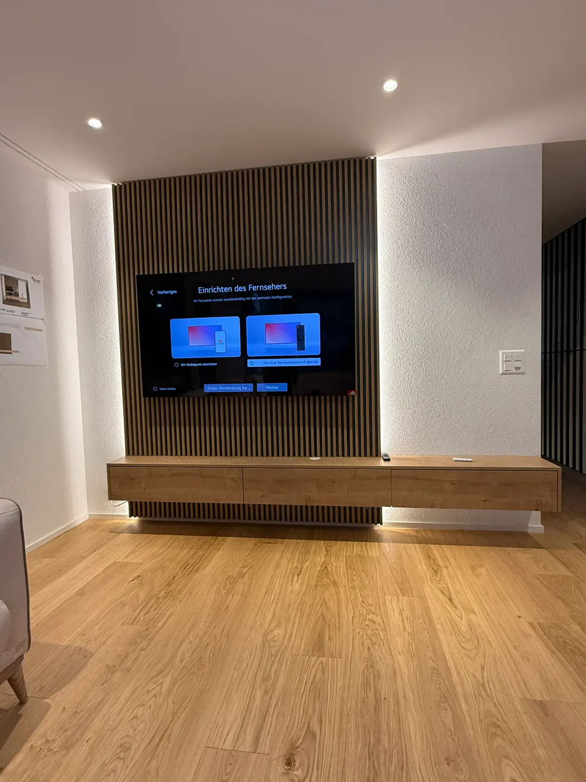 Moderne TV-Kommode aus Holz mit schwebender Konstruktion und vertikaler Lamellenwand hinter dem Fernseher